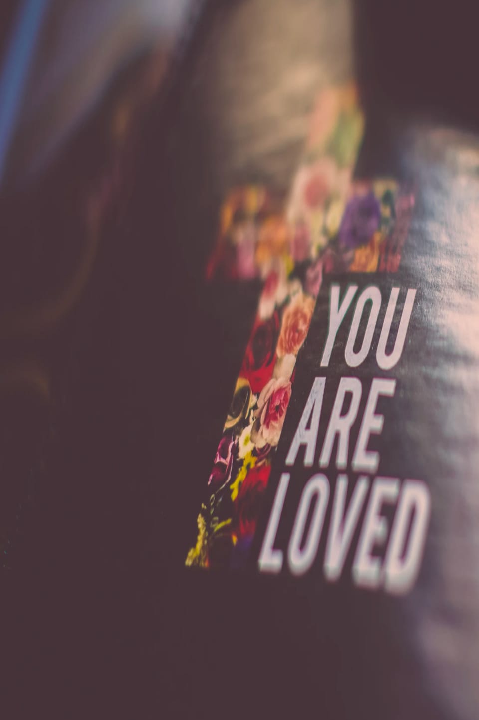 The words “You are loved” printed beside a pattern of colourful roses